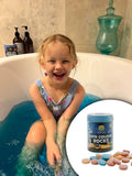 Child in a bathtub with bath color rocks and bath bombs changing bath water colour