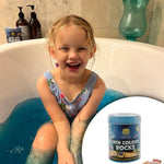 Child in a bathtub with bath color rocks and bath bombs changing bath water colour