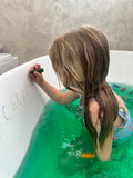 Child writing on a bath with a bath colours 
